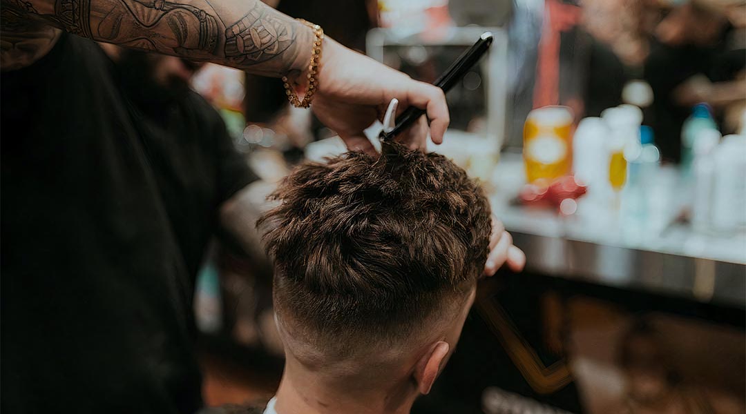 male barber performing a haircut on a client